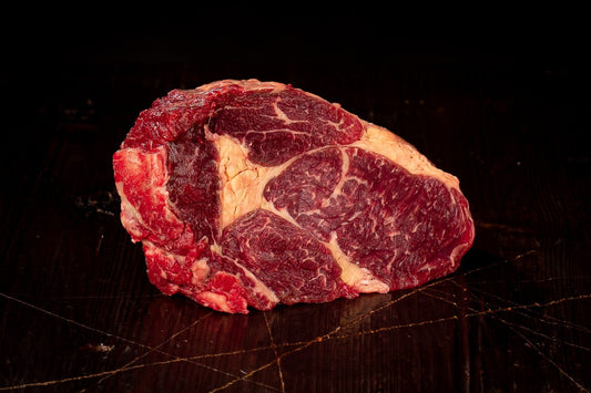 Bio-Ribeye mit sichtbarer Marmorierung auf dunklem Holz