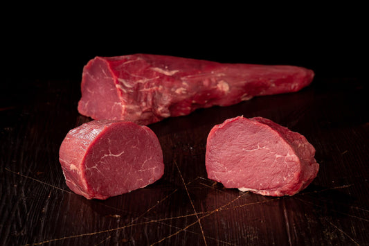 Bio-Rinderfilet am Stück und zwei Filetmedaillons auf dunklem Holz
